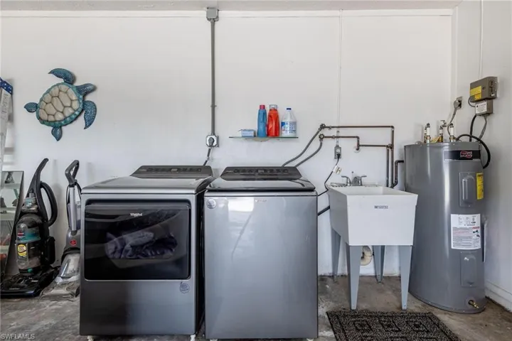 Laundry room featuring electric water heater, sink, and washer and clothes dryer
