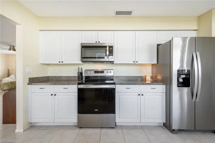 Kitchen featuring stainless steel appliances, white cabinetry, and light tile patterned floors