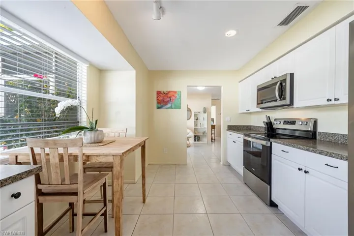 Kitchen with stainless steel appliances, white cabinetry, and light tile patterned floors