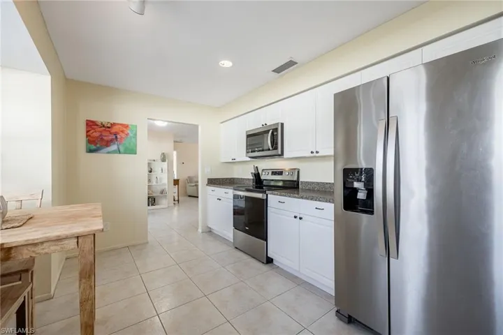 Kitchen with white cabinetry, stainless steel appliances, and light tile patterned flooring