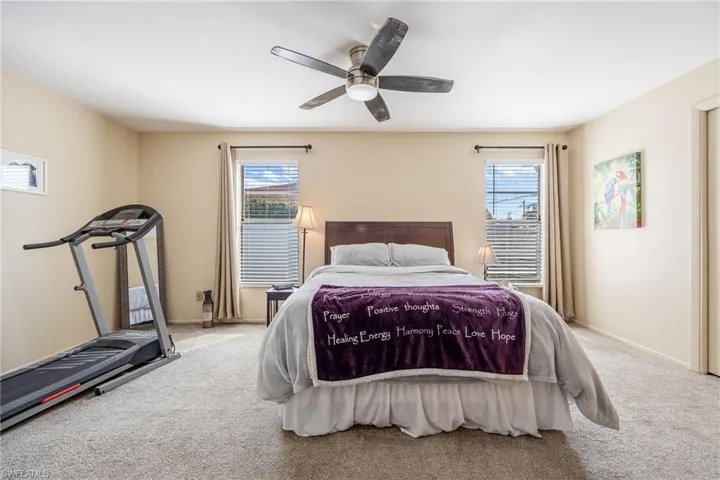 Bedroom with multiple windows, ceiling fan, and carpet