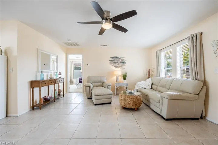 Living room with ceiling fan and light tile patterned flooring