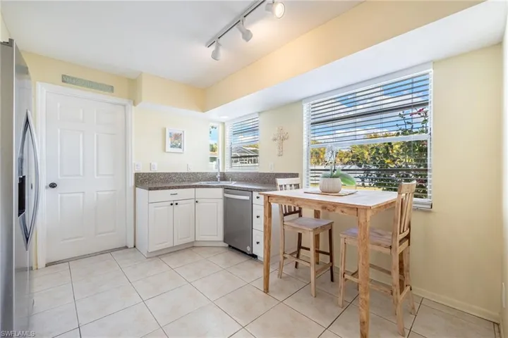 Kitchen with light tile patterned flooring, rail lighting, sink, white cabinetry, and appliances with stainless steel finishes