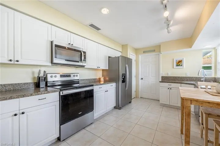 Kitchen featuring white cabinetry, light tile patterned floors, sink, and appliances with stainless steel finishes