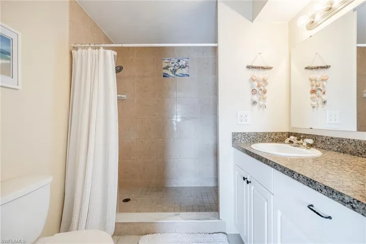 Bathroom featuring a shower with curtain, vanity, and toilet