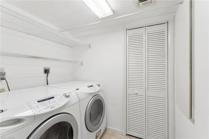 Laundry area featuring a textured ceiling, washer and dryer, laundry area, and visible vents