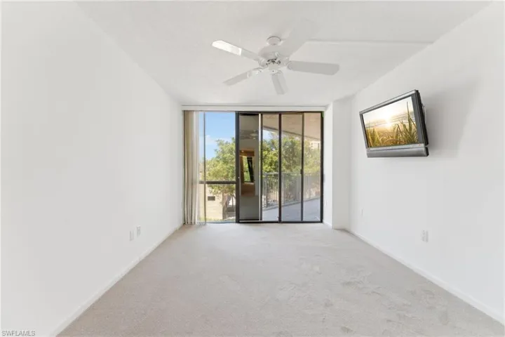 Carpeted empty room with a wall of windows, baseboards, and a ceiling fan