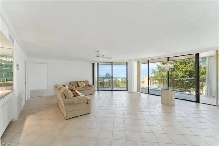 Living room with crown molding, light tile patterned floors, floor to ceiling windows, visible vents, and ceiling fan