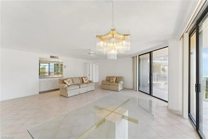 Unfurnished living room featuring light tile patterned floors, ceiling fan with notable chandelier, baseboards, a textured ceiling, and visible vents