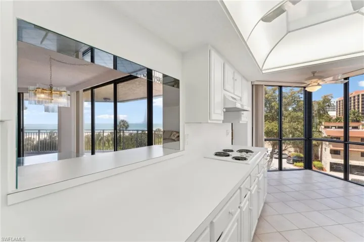 Kitchen with white cabinetry, light countertops, light tile patterned floors, under cabinet range hood, and white electric cooktop
