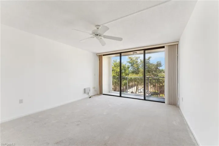 Carpeted empty room featuring a textured ceiling, baseboards, expansive windows, and ceiling fan