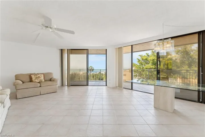 Unfurnished living room featuring expansive windows, a textured ceiling, ceiling fan with notable chandelier, and light tile patterned floors