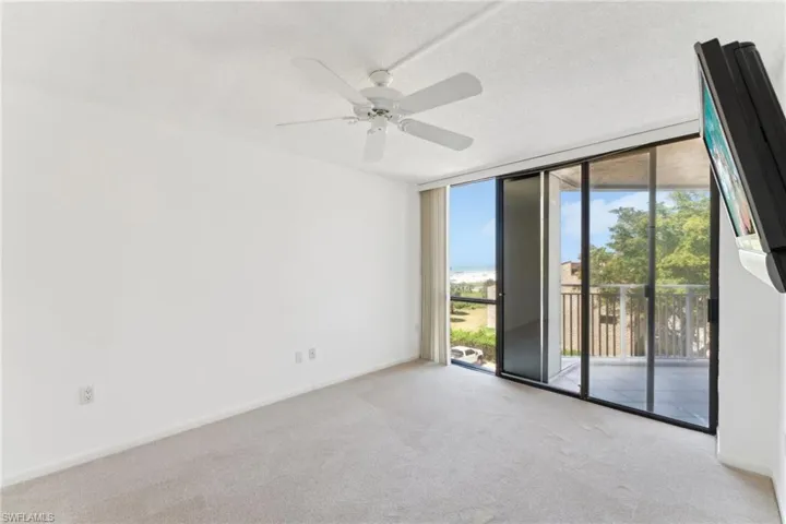 Carpeted empty room with a wall of windows, ceiling fan, baseboards, and a textured ceiling