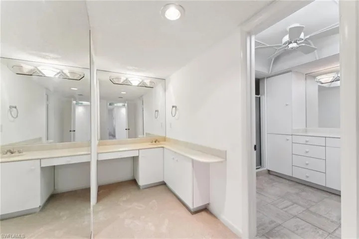 Full bath featuring baseboards, a ceiling fan, a sink, and two vanities