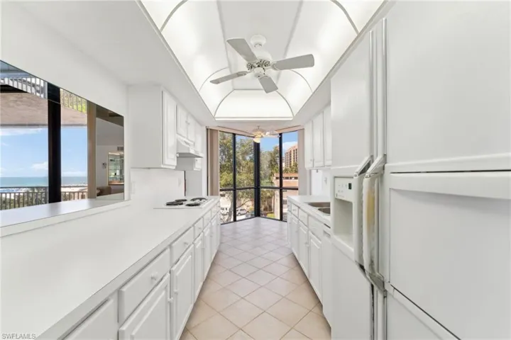 Kitchen featuring light countertops, white cabinets, white appliances, under cabinet range hood, and light tile patterned floors
