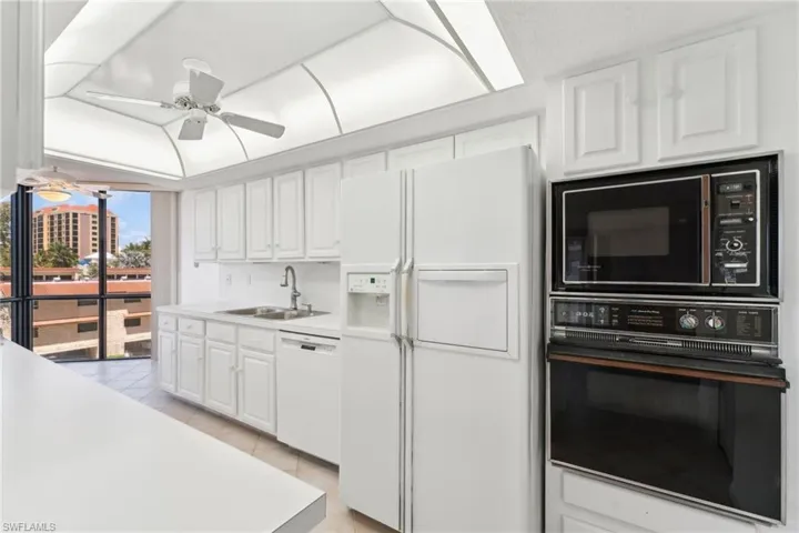 Kitchen featuring white cabinets, a sink, light tile patterned floors, and white appliances