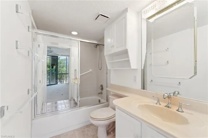 Bathroom featuring toilet, vanity, a textured ceiling, bath / shower combo with glass door, and visible vents