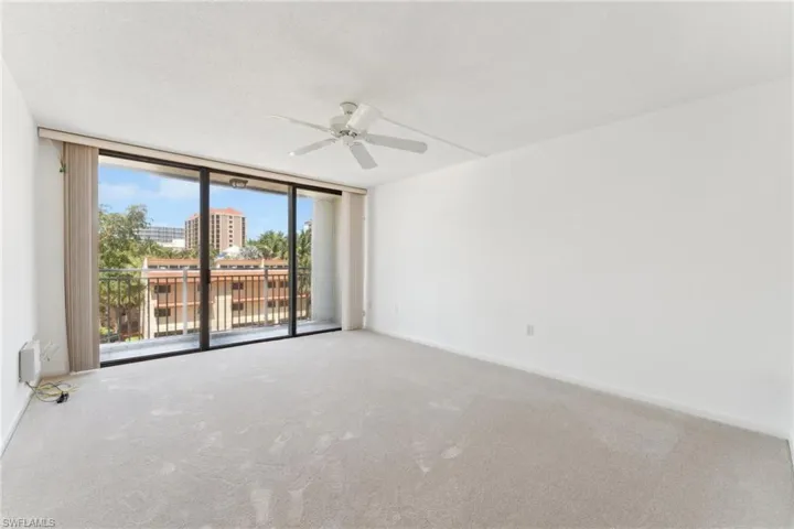 Carpeted empty room with a wall of windows, a textured ceiling, baseboards, and a ceiling fan