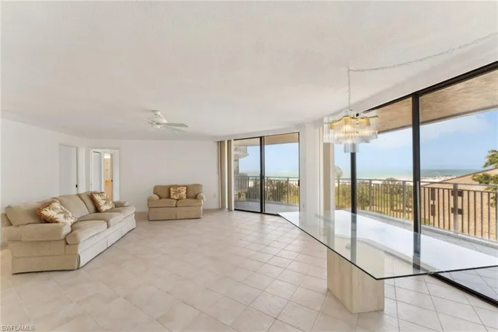 Unfurnished living room with ceiling fan with notable chandelier, floor to ceiling windows, light tile patterned floors, and a textured ceiling