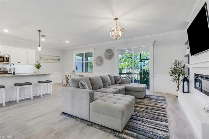 Living room featuring crown molding, suspended lighting, and a glass covered fireplace