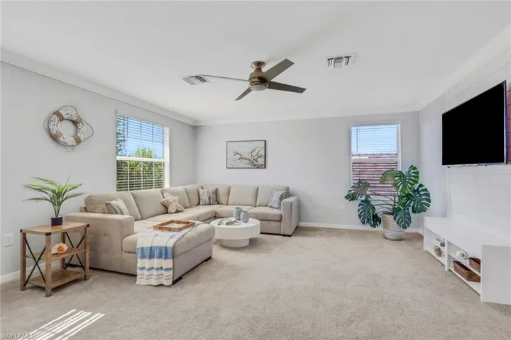 Living room featuring ceiling fan, carpet, and ornamental molding