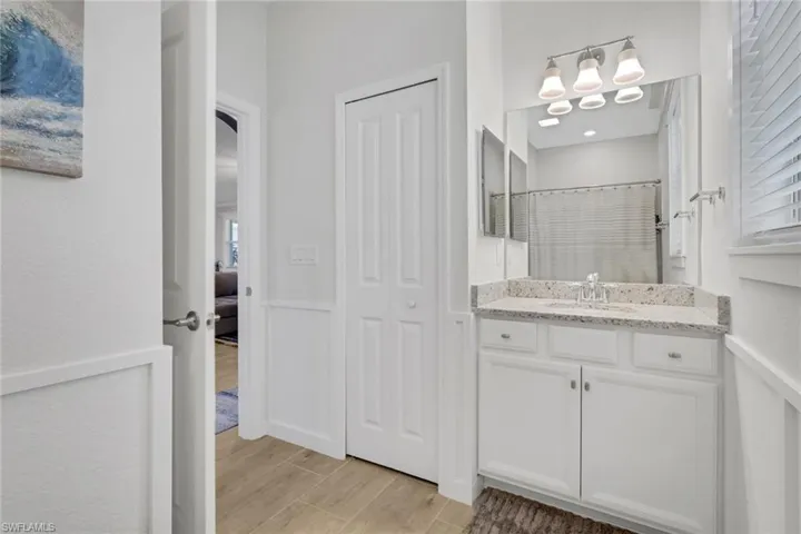 Bathroom featuring a shower with shower curtain, vanity, wood finish floors, and a closet