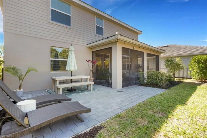 Rear view of house with a sunroom, stucco siding, a patio, and outdoor dining area