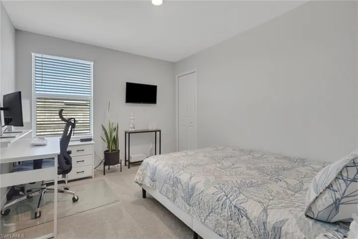 Bedroom with a desk and light colored carpet