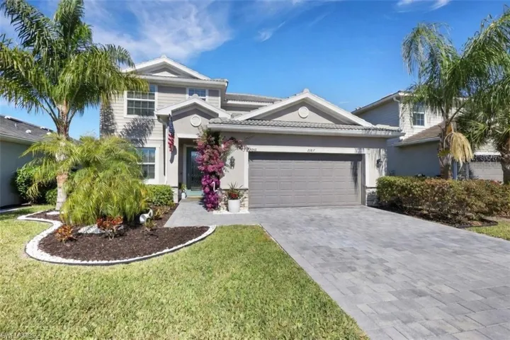View of front of house featuring a garage, decorative driveway, stucco siding, and a front lawn