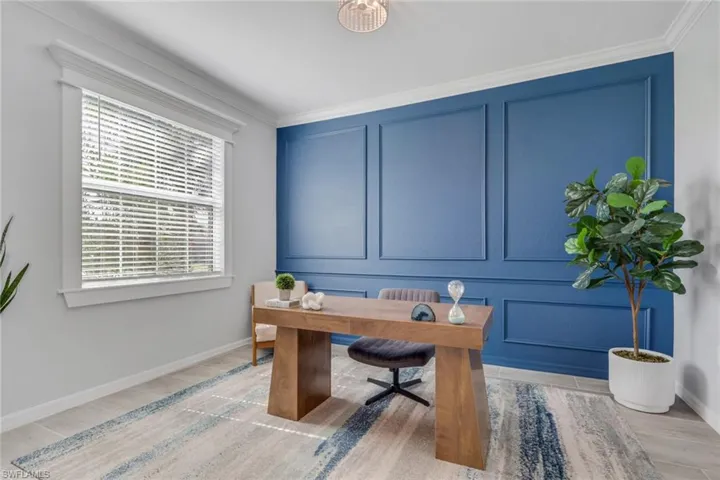 Office with a decorative wall, light wood-style flooring, and crown molding