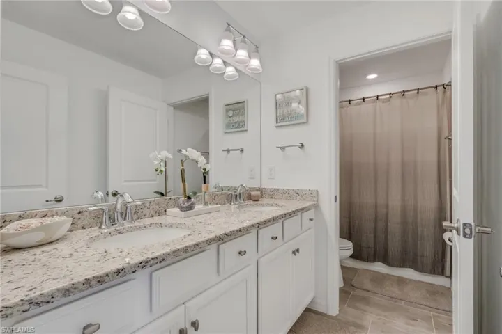 Full bathroom featuring double vanity and toilet