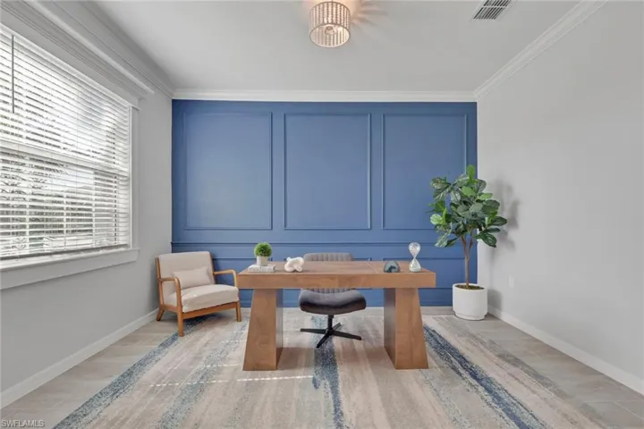Home office featuring a decorative wall, light wood-style flooring, and ornamental molding
