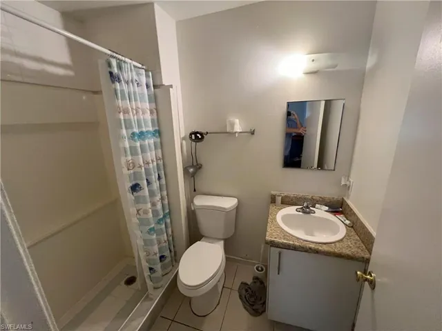 Bathroom featuring tile patterned floors, vanity, curtained shower, and toilet