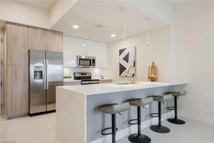 Kitchen featuring recessed lighting, a sink, a peninsula, a kitchen bar, and appliances with stainless steel finishes