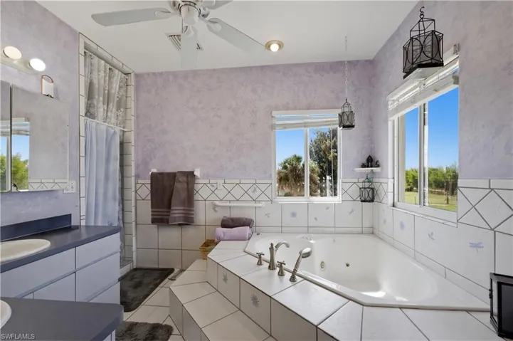 Full bathroom with vanity, a tub with jets, light tile patterned flooring, tile walls, and a shower stall