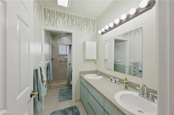Full bathroom with double vanity and a shower stall