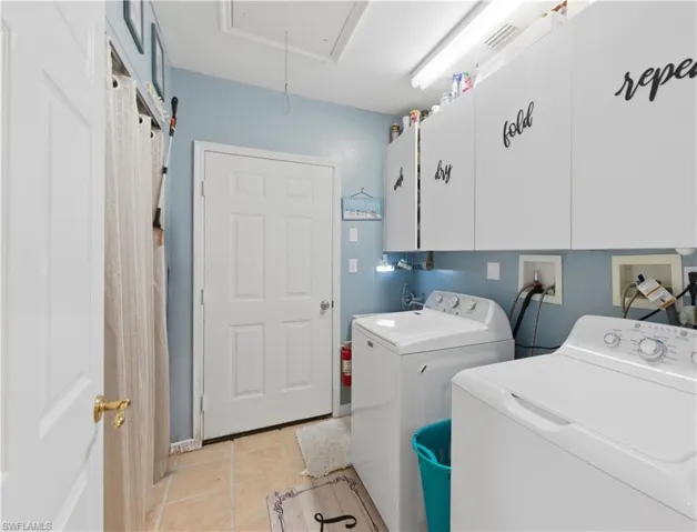 Laundry room featuring cabinet space, light tile patterned flooring, and separate washer and dryer