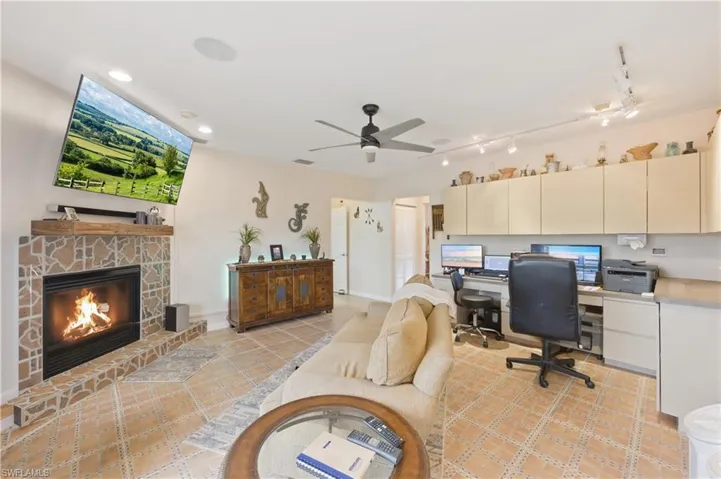 Office space featuring a ceiling fan, a stone fireplace, and light tile patterned floors