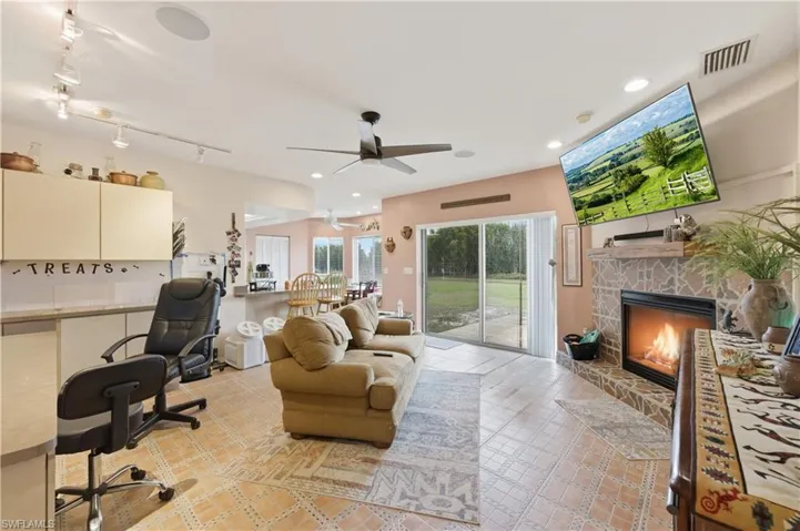 Office space with a stone fireplace, ceiling fan, and track lighting