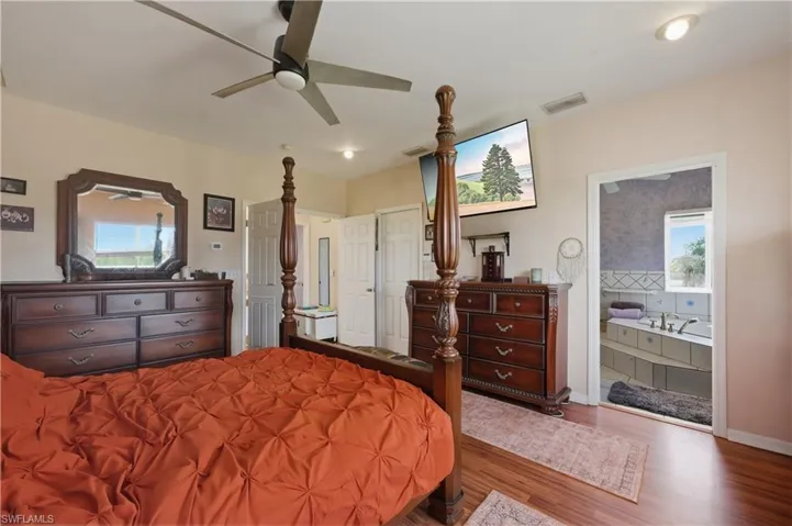 Bedroom featuring connected bathroom, wood finished floors, a ceiling fan, and recessed lighting
