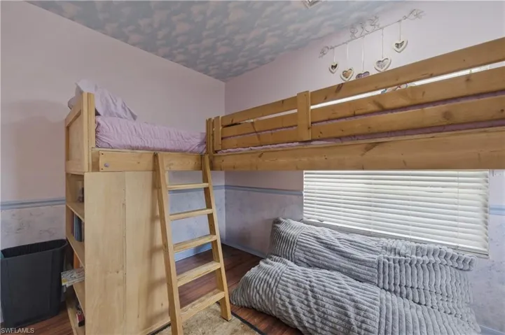 Bedroom with wood finished floors and a wainscoted wall