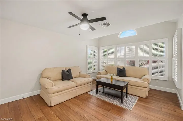 Sunroom/optional 3rd bedroom conversion, Wood-finish flooring throughout, vaulted ceiling, arched transom window, and white plantation shutters