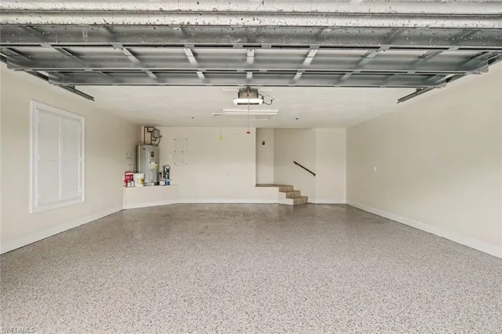 Spacious garage featuring a speckled epoxy floor, white walls, and a window with horizontal blinds
