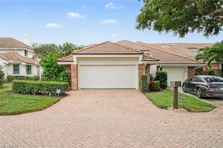 Brick paver driveway with integrated landscaping and a two-car garage