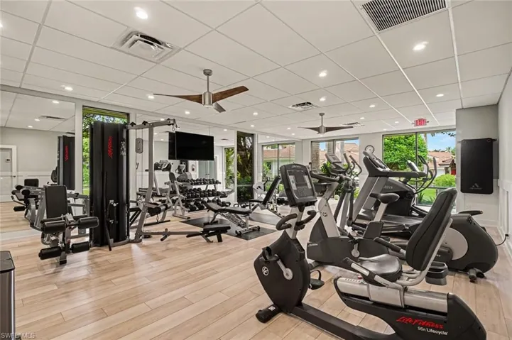 Wood-finish flooring with full-height mirrors, recessed lighting, and ceiling fans in clubhouse