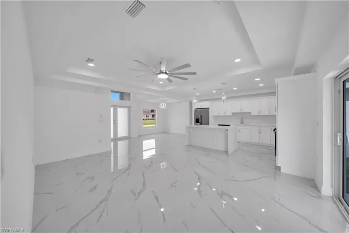 Open-concept living space featuring high ceilings, recessed lighting, a ceiling fan, and large format tile flooring