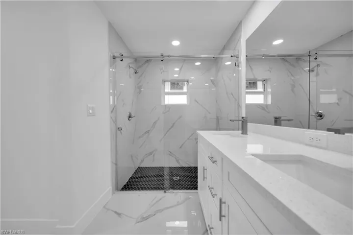 Walk-in shower with clear glass barn doors, tile surround, and mosaic tile flooring
