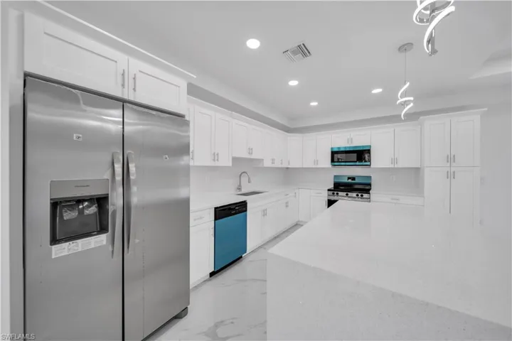 Modern kitchen featuring white shaker cabinetry, white countertops, stainless steel appliances, and recessed lighting