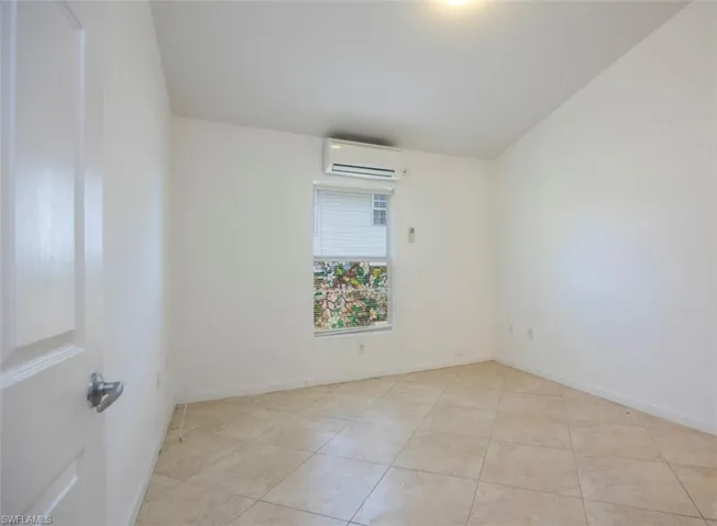 Empty room featuring baseboards, light tile patterned flooring, and a wall mounted AC