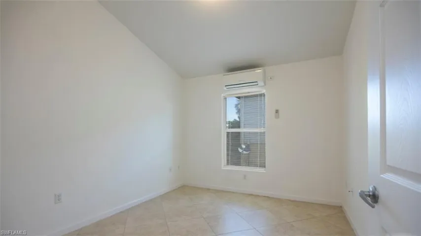 Spare room featuring light tile patterned floors, baseboards, and a wall mounted air conditioner